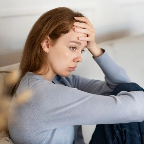 Femme anxieuse assise, la main sur le front