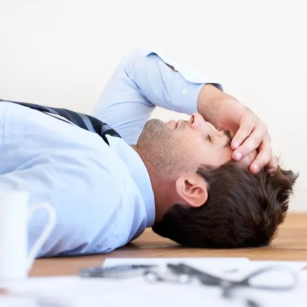 Homme allongé sur un bureau, épuisé par le stress et le burn-out